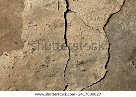 Crack in the concrete cladding of an old house. Rough, uneven surface. Cement plaster on a brick wall, texture, background. Ancient backdrop of yellowed color. Yellow, faded view of the wall cladding Royalty-Free Stock Photo #2417880829