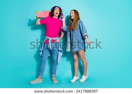 Full length photo of young teen girlfriend boyfriend have fun holding props vintage phone and skateboard isolated on cyan color background Royalty-Free Stock Photo #2417888307