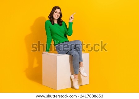 Full body length photo of model woman brunette sitting on podium point finger benefits her agency isolated over yellow color background Royalty-Free Stock Photo #2417888653