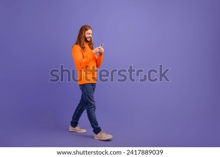 Full body size photo of strolling happy young man with cellphone interested betting gambling games isolated on purple color background