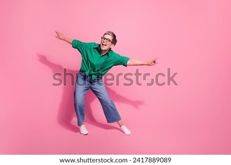 Full body photo of attractive pensioner woman dance energetic moving party dressed stylish green clothes isolated on pink color background