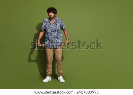 Full body size photo of young funny hispanic migrant guy show his money balance empty pockets in pants isolated on khaki color background