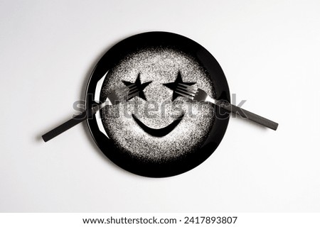 Smiling face, concept made with plate and flour, white background, star shaped eyes, black plate, happy mood, facial expressions, forks in the shape of arms with different positions