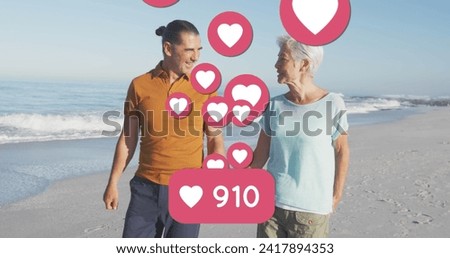 Image of red heart love digital icons and numbers over smiling senior couple on beach. digital interface, social media and global networking concept digitally generated image.