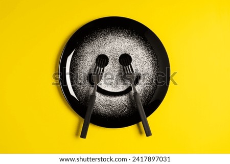 Smiling face, concept made with plate and flour, yellow background, star shaped eyes, black plate, happy mood, facial expressions, forks in the shape of arms with different positions