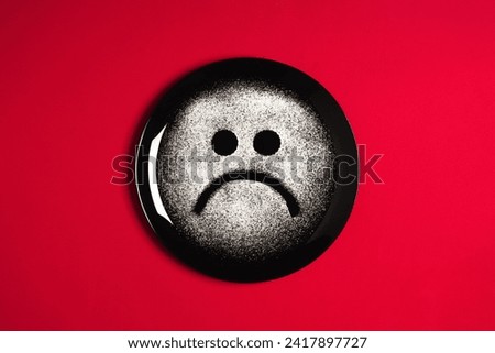 Sad face, concept made with plate and flour, red background, star shaped eyes, black plate, happy mood, facial expressions