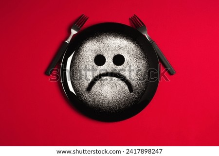 Sad face, concept made with plate and flour, red background, star shaped eyes, black plate, happy mood, facial expressions, forks in the shape of arms with different positions