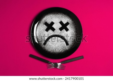 Sad face, concept made with plate and flour, majenta background, x-shaped eyes, black plate, happy mood, facial expressions, forks in the shape of arms with different positions