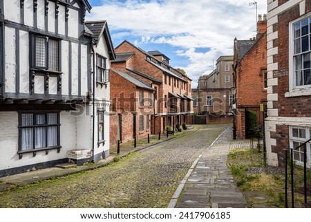 Empty cobbled street lined with brick houses on a partly cloudy summer day