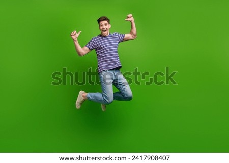 Full length photo of impressed man wear stylish t-shirt jeans trousers jumping directign at himself isolated on green color background