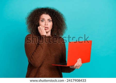 Photo portrait of attractive young woman bite nails hold netbook dressed stylish brown clothes isolated on aquamarine color background