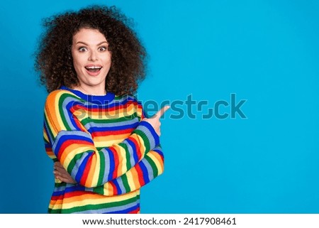 Photo portrait of attractive young woman point excited empty space dressed stylish rainbow print clothes isolated on blue color background