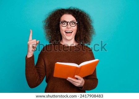 Portrait of young excited funky woman student with copybook point finger up shocked found correct formula isolated on cyan color background