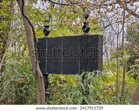 The back of a large steel sign in the woods.