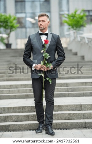 special occasion formalwear. romantic man with rose for special occasion. tuxedo man outdoor Royalty-Free Stock Photo #2417932561