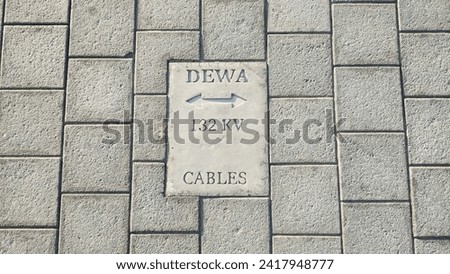 Dubai Electricity and Water Authority Government agency sign with 132kv cables warning on a ground stone paved floor. Closeup top view.