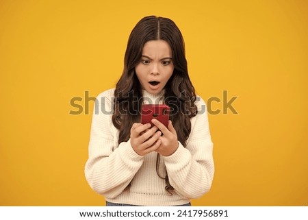 Mobile online shopping. Cute teen child girl paying with phone, texting and chatting on smartphone. Surprised teenager girl.