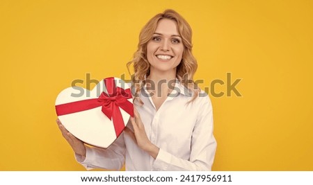 happy woman with present heart box on yellow background