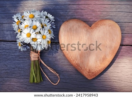 Wooden heart and a bouquet of daisies