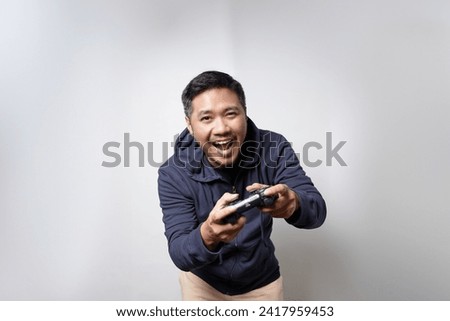 Male gamer with a joystick in his hand who is happy over victory in a video game game on an isolated white background. Emotional player. Portable game console