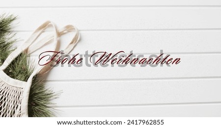 Frohe weihnachten text in red over shopping bag with christmas bracnhes on white wood background. Christmas, decorations, tradition, german, greetings and celebration digitally generated image.