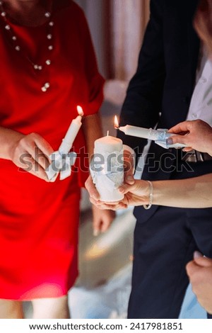 The person appears to be indoors and is standing while holding the candle. The individual is wearing wedding attire.