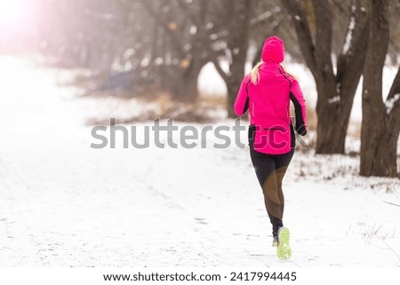 Picture of young sportswoman running in winter forest