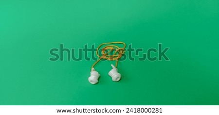 Ear plug to Reduce Noise Isolated on green Background. Earplugs protect ears from noise.