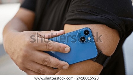 Confident young latin man harnessing technology, scanning his diabetes sensor with smartphone on city street, monitoring glucose levels with a smile Royalty-Free Stock Photo #2418015923