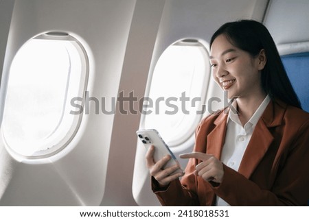 young woman hand using modern smartphone in airplane, businessman typing message during flight, business trip, people working in airplane on mobile phone.