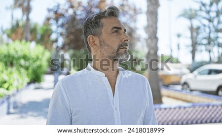 Young hispanic grey-haired man looking to the sky with serious face at park Royalty-Free Stock Photo #2418018999