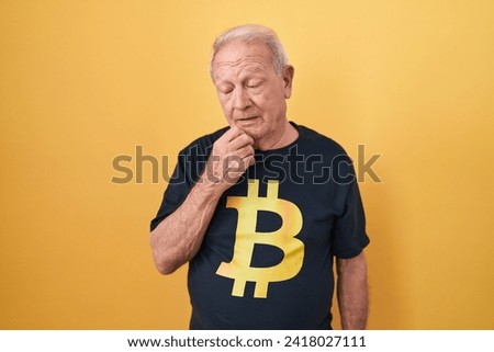 Senior man with grey hair wearing bitcoin t shirt looking sleepy and tired, exhausted for fatigue and hangover, lazy eyes in the morning. 