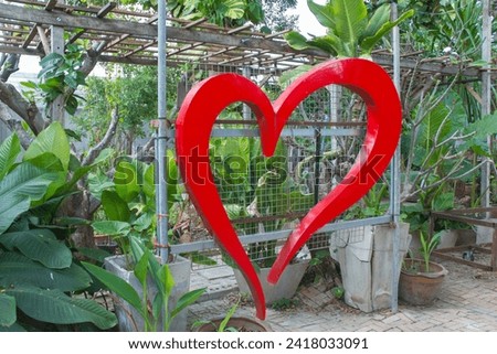 A red heart-shaped wrought iron for Valentine's Day is placed in the backyard ornamental garden as an angle for taking photos.