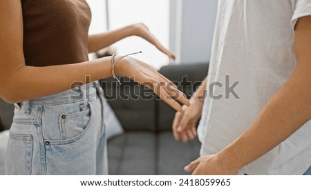 An interracial couple gestures during a discussion in a home interior with focus on expressing emotions and body language. Royalty-Free Stock Photo #2418059965