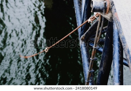 Wire rope attach to railing of suspension bridge over the river.