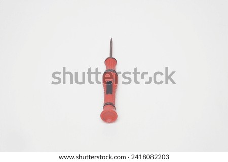 A small red cell phone screwdriver with flat lay made of plastic on a white background
