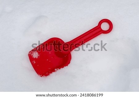 Red children's sand shovel. Plastic toy. A child digs snow. The child makes a snow figure.