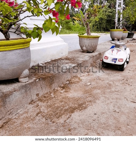 A toy car parked next to a flowerpot