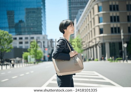 Female office worker in her 30s walking in the business district Royalty-Free Stock Photo #2418101335