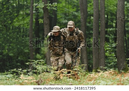 Elite soldier displays unwavering camaraderie and compassion as he aids his injured comrade, skillfully extracting him from the forest with a stretcher, showcasing the profound bond and selflessness Royalty-Free Stock Photo #2418117395