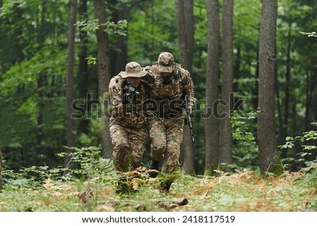 Elite soldier displays unwavering camaraderie and compassion as he aids his injured comrade, skillfully extracting him from the forest with a stretcher, showcasing the profound bond and selflessness Royalty-Free Stock Photo #2418117519