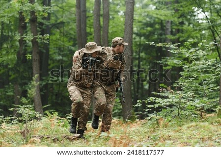 Elite soldier displays unwavering camaraderie and compassion as he aids his injured comrade, skillfully extracting him from the forest with a stretcher, showcasing the profound bond and selflessness Royalty-Free Stock Photo #2418117577