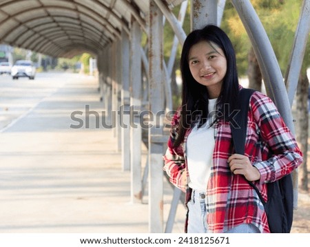 Asian girl hold book and backpack at school.