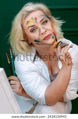 Close up portrait of smiling beautiful  artist woman painter . Face smeared with colors. 