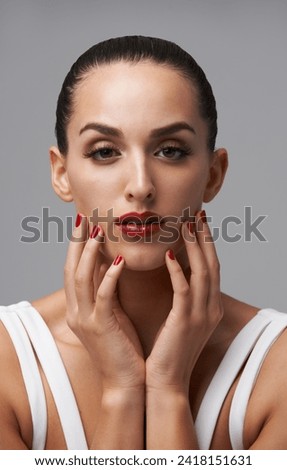 Woman, portrait and red lipstick with beauty and manicure, nail polish and cosmetic care for skin on grey background. Face, confidence and bold makeup with hands and color nails for glamour in studio Royalty-Free Stock Photo #2418151631