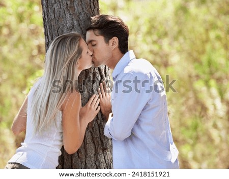 Couple, kiss and love by tree in nature for love, romance or affection at outdoor park or forest. Face of man and woman touching lips for natural embrace, relationship or bonding in woods for date Royalty-Free Stock Photo #2418151921