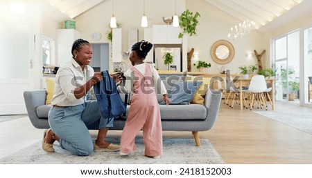Talking, happy and a mother with a child getting ready for school in the morning. Kiss, laughing and an African mom helping a little girl with a bag in the living room of a house for kindergarten Royalty-Free Stock Photo #2418152003