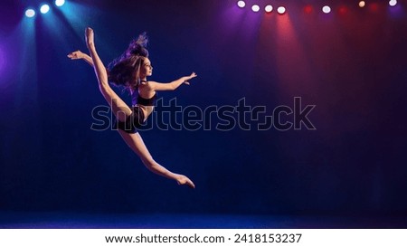 Beautiful young performer of modern choreography dancing in the spotlights on a black background.