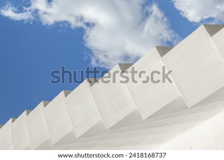 Abstract architecture background. Modern white concrete structure, stairs steps,  geometric shapes pattern, against blue sky with clouds. Contemporary, minimalist concept. Architectural photography