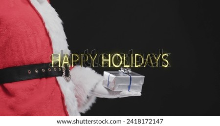 Happy holidays text in gold over father christmas holding present on black background. Christmas, tradition, greetings and celebration digitally generated image.